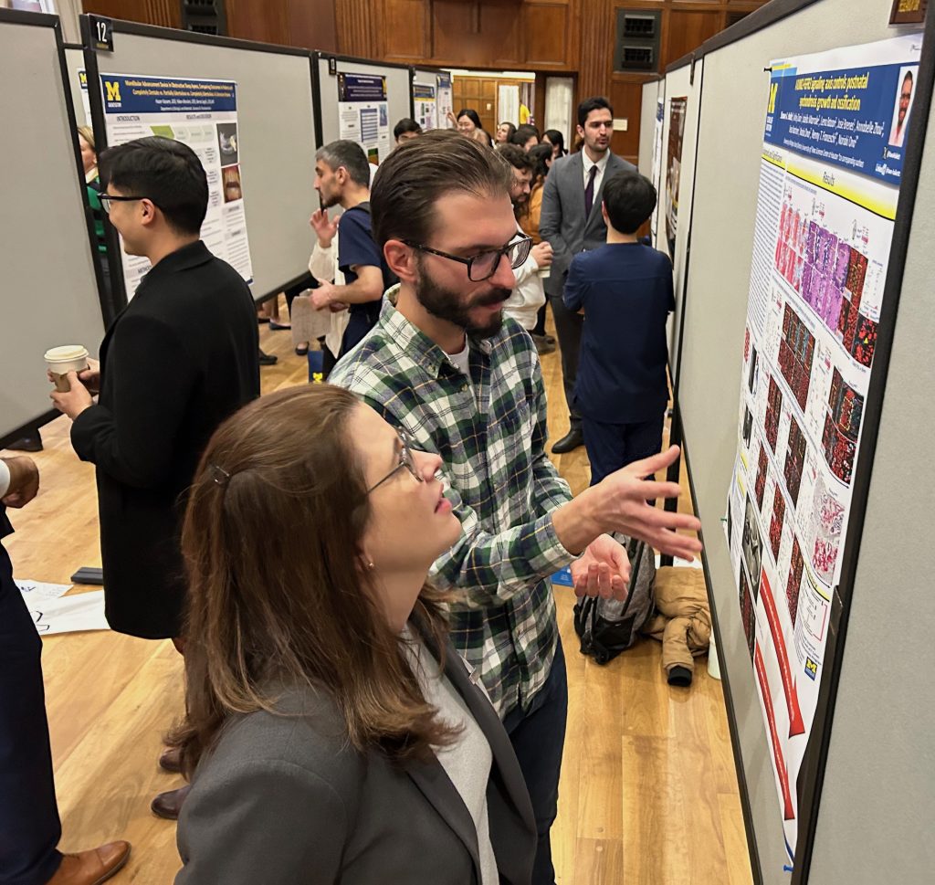 Shawn Hallet, a dual DDS-PhD student, discusses his research, "A RUNX2-FGFR3 signaling axis controls postnatal synchondrosis growth and ossification" with faculty judge Livia Tenuta during the afternoon poster session.