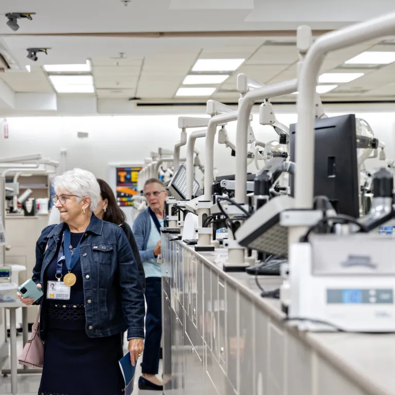three people on a tour through a lab